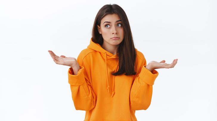 Mujer con gesto de no saber nada en una chaqueta naranja